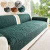 A dark green plush sofa cover with an embossed pattern displayed on a white sofa.