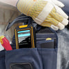 A hand wearing a yellow glove is holding a small, orange multi-function wall scanner device in a pocket.