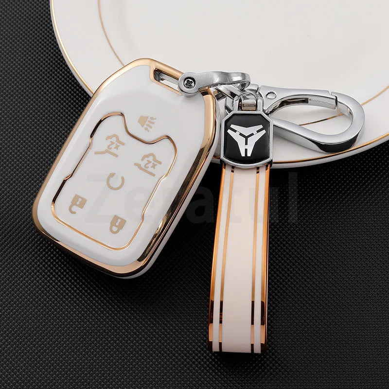 A white TPU smart key fob cover with a gold clip attached to a leather strap and a silver keyring.