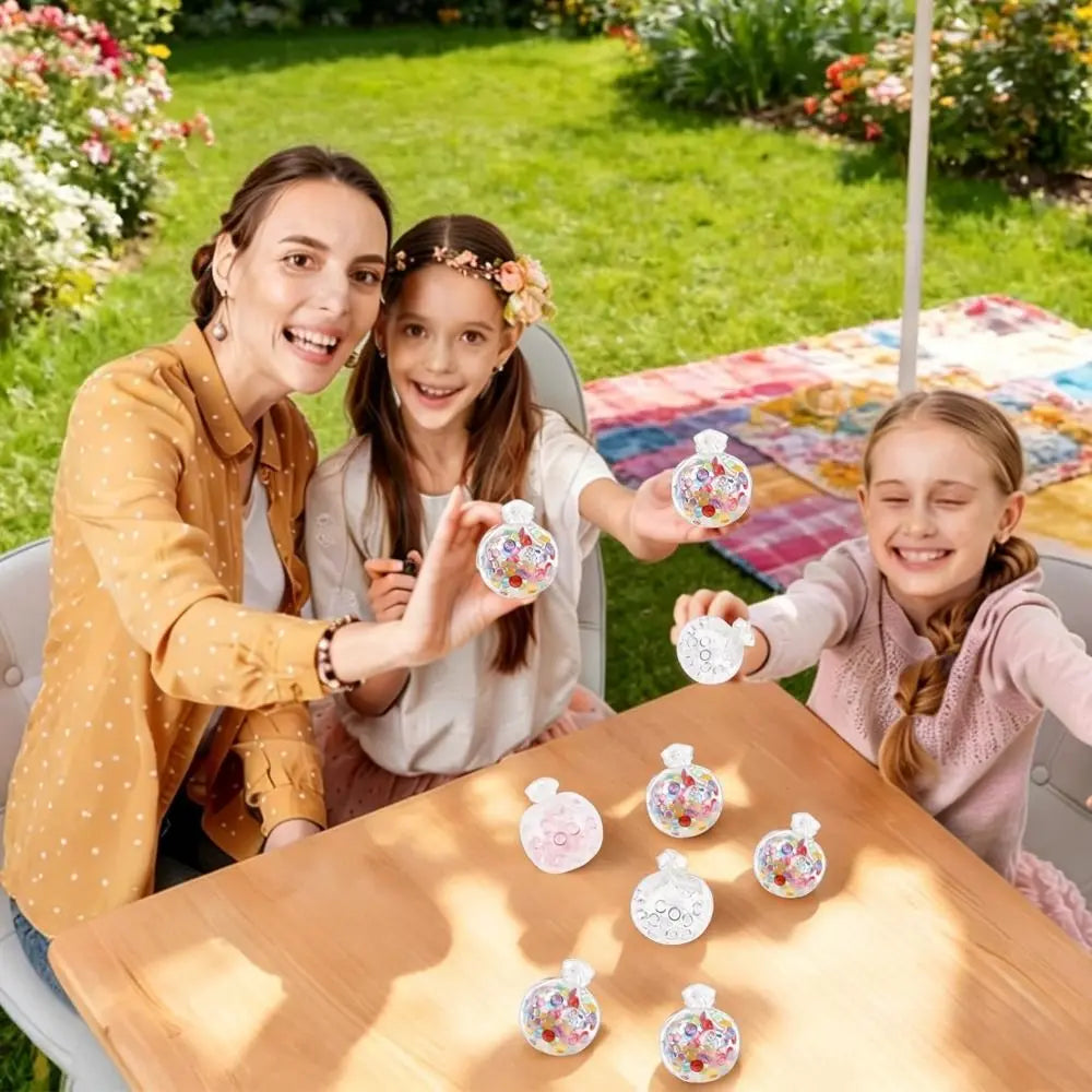 Drei Kinder lächeln und zeigen verschiedene „Squishy“-Stressballchen auf einem Holztable.