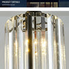 A modern crystal pendant light featuring a clear glass shade and an iron frame, illuminated from within.