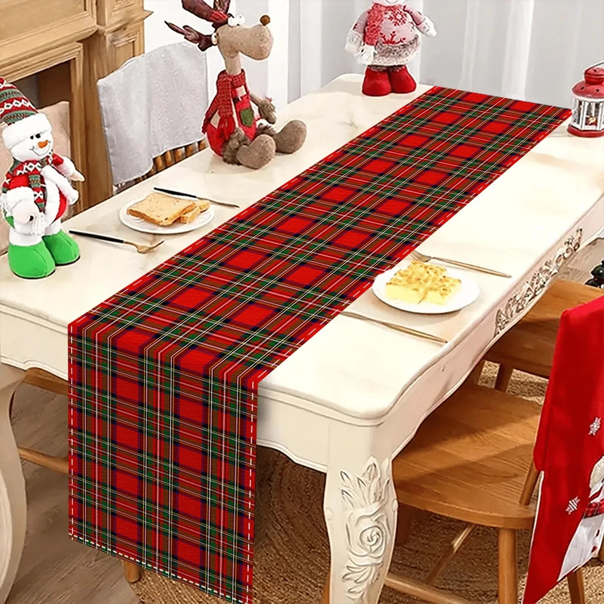 A red and green tartan Christmas table runner displayed on a white dining table with festive decorations.