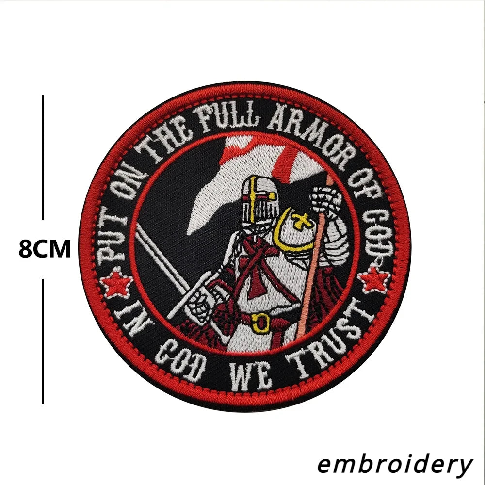 A circular embroidered patch featuring a stylized archangel figure and text that reads Put on the full armor of God we trust