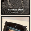 A close-up of a black shoulder bag showing the hardware chain and internal capacity.