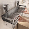 A hand is installing a stainless steel wall-mounted shower caddy with suction cups onto a bathroom tile.