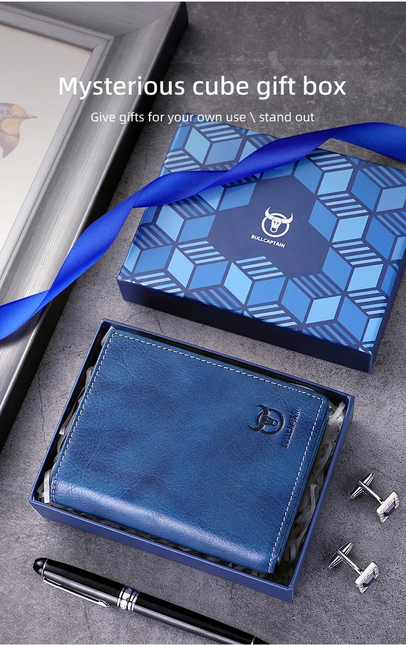 A blue leather bifold wallet is displayed in its box alongside a pen and keys.