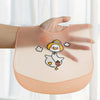 A hand holds an orange silicone baby bib featuring a cute cartoon duck with an orange and white design.