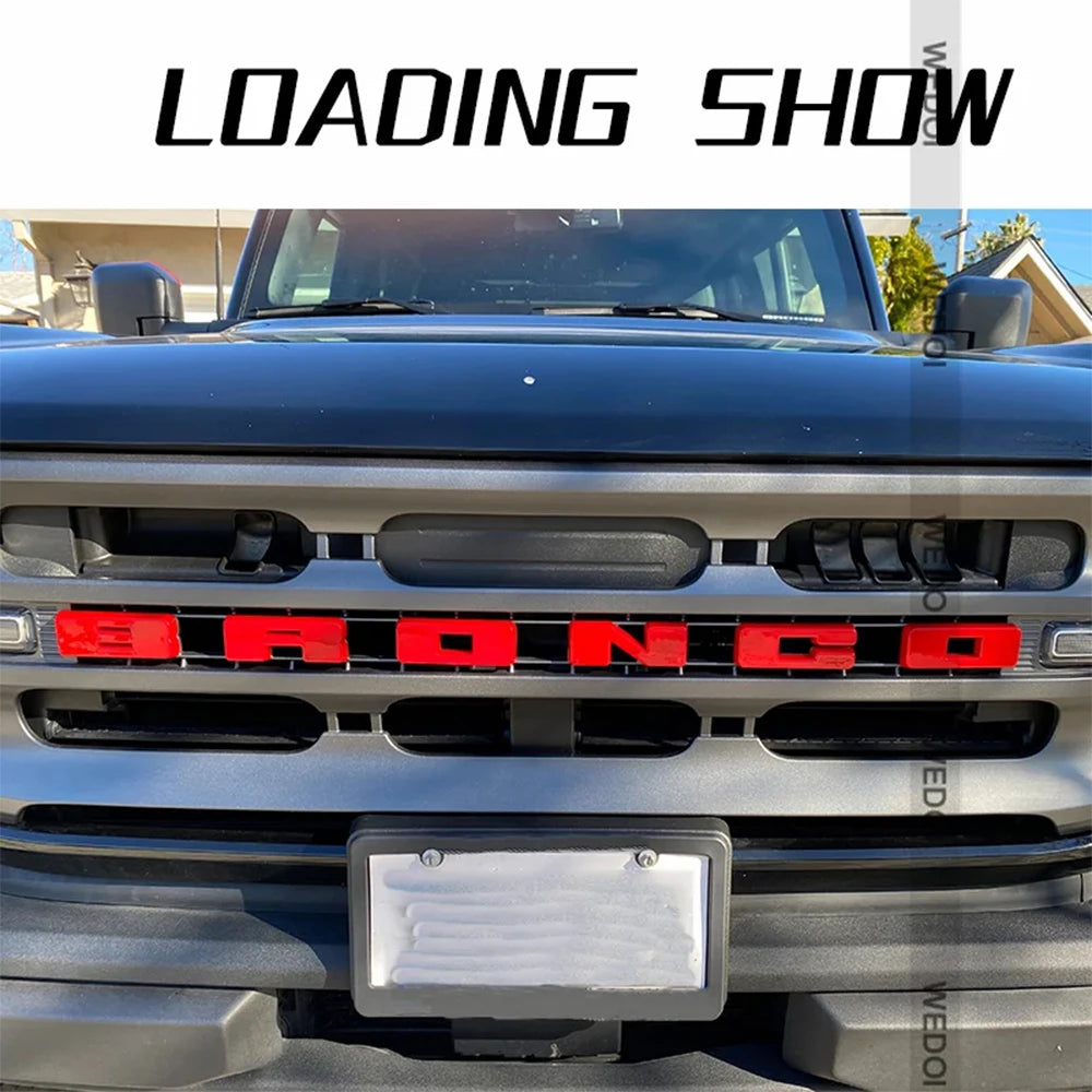 Close-up of a black Ford Bronco grille with a red lettering emblem cover installed.
