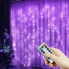 A hand holds a remote control for USB LED curtain string lights illuminating purple sheer curtains.