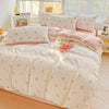 A floral duvet cover set in soft pink and cream tones displayed on a bed with natural light.