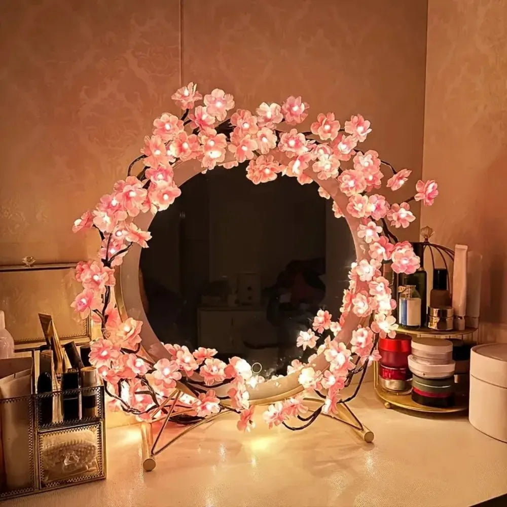 A circular wreath made of pink cherry blossom string lights with flower vines displayed on a table.