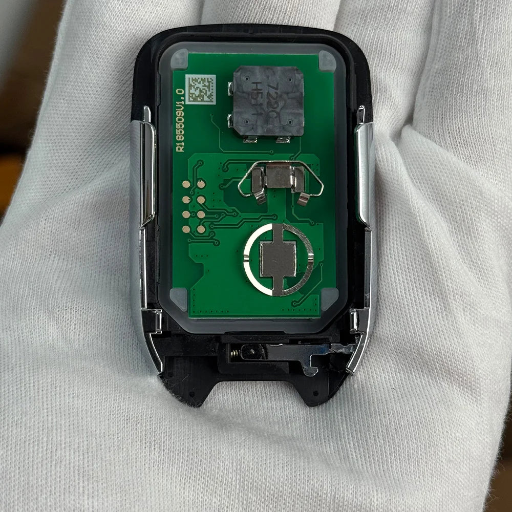 A close-up view of a replacement remote key electronic module with a green circuit board held in a hand.