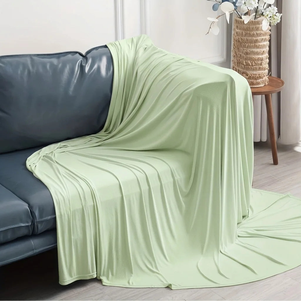 Light green ice silk blanket draped over a dark blue sofa.