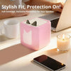 A pink silicone protective case for a speaker is shown next to a white mug and a laptop.