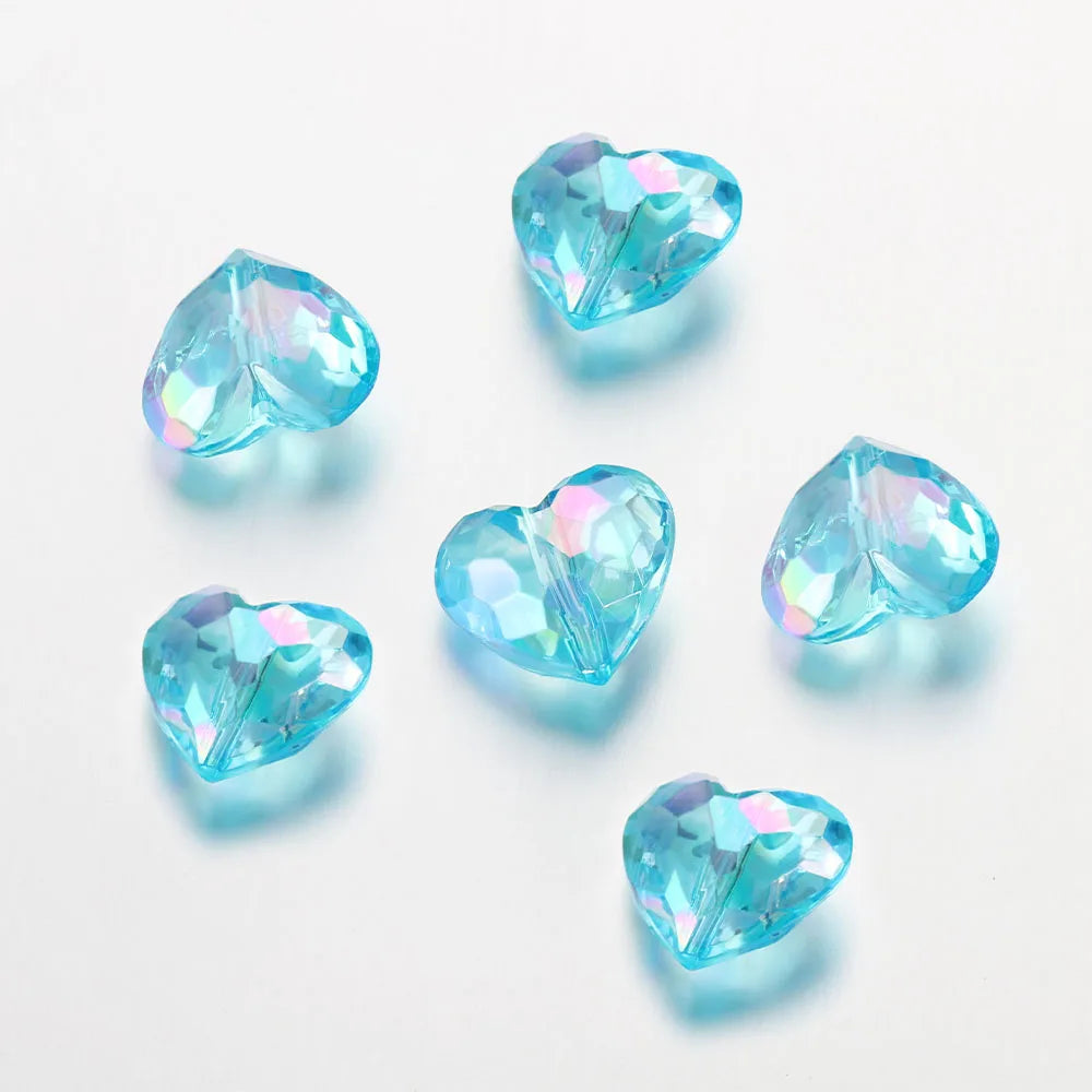 A collection of twenty clear blue acrylic heart-shaped beads scattered on a white surface.