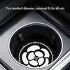 A close-up view of a black camellia flower pattern coaster fitting into a car cup holder.