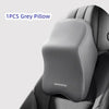 A single grey memory foam car headrest pillow with shoulder support placed on a dark upholstery.