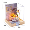 A miniature Japanese sakura tea house kit displayed in a clear acrylic box with interior decor and an LED light.