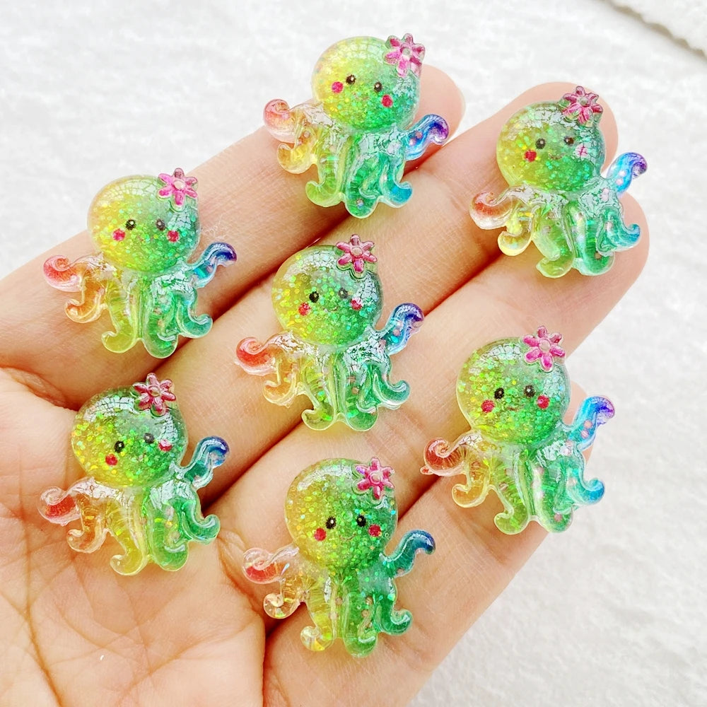 A hand holds several bright green and yellow resin charms shaped like sea creatures for crafting