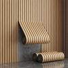 A close-up of wood grain peel-and-stick wall tiles installed vertically on a textured gray wall.