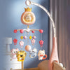 A pink baby crib mobile with a crown topper and hanging toys, featuring a light projector.