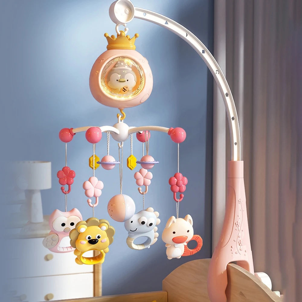 A pink baby crib mobile with a crown topper and hanging toys, featuring a light projector.
