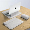 A white slim laptop sleeve case is shown resting on a wooden table next to an Apple laptop.
