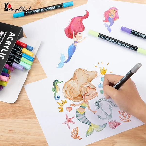 يد تمسك بقلم حبر مزدوج لرسم تصميم حورية بحر على ورق أبيض مع أقلام وأدوات فنية