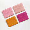 Three pink and magenta genuine leather slim card holder wallets displayed on a white background.