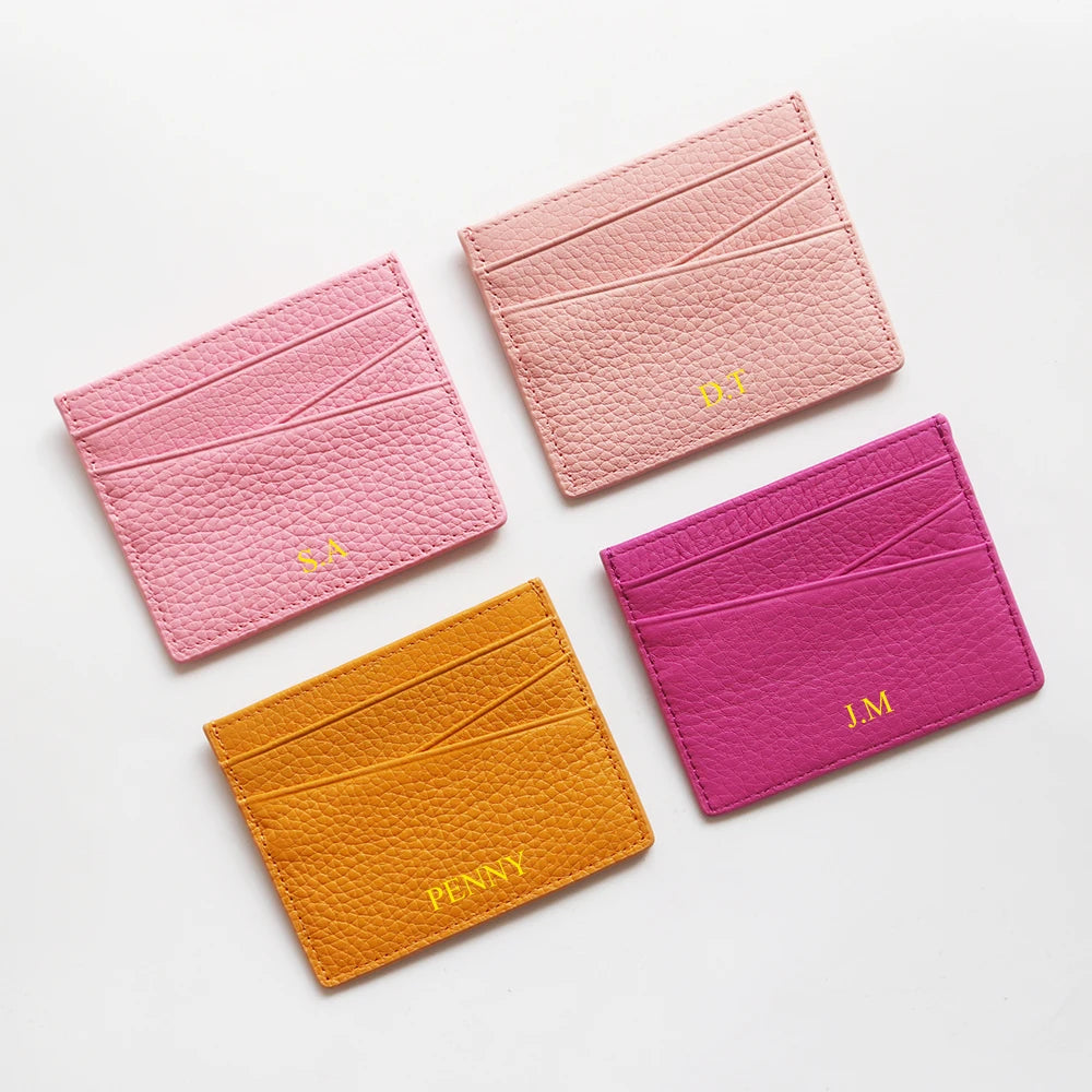 Three pink and magenta genuine leather slim card holder wallets displayed on a white background.