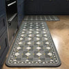 A rectangular gray kitchen rug with a classic Persian print and yellow accents placed on a light wood floor.