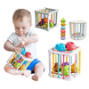 A baby is playing with a colorful rainbow shape sorter cube toy for learning.