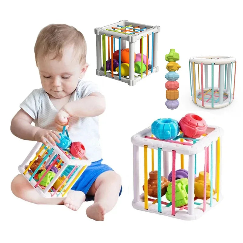 A baby is playing with a colorful rainbow shape sorter cube toy for learning.