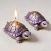 A small purple lotus flower silicone mold shaped like a turtle with a lit candle.