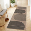 A long runner rug with geometric black and beige stripes laid on a light wood floor.