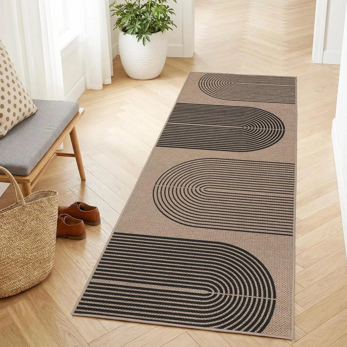 A long runner rug with geometric black and beige stripes laid on a light wood floor.