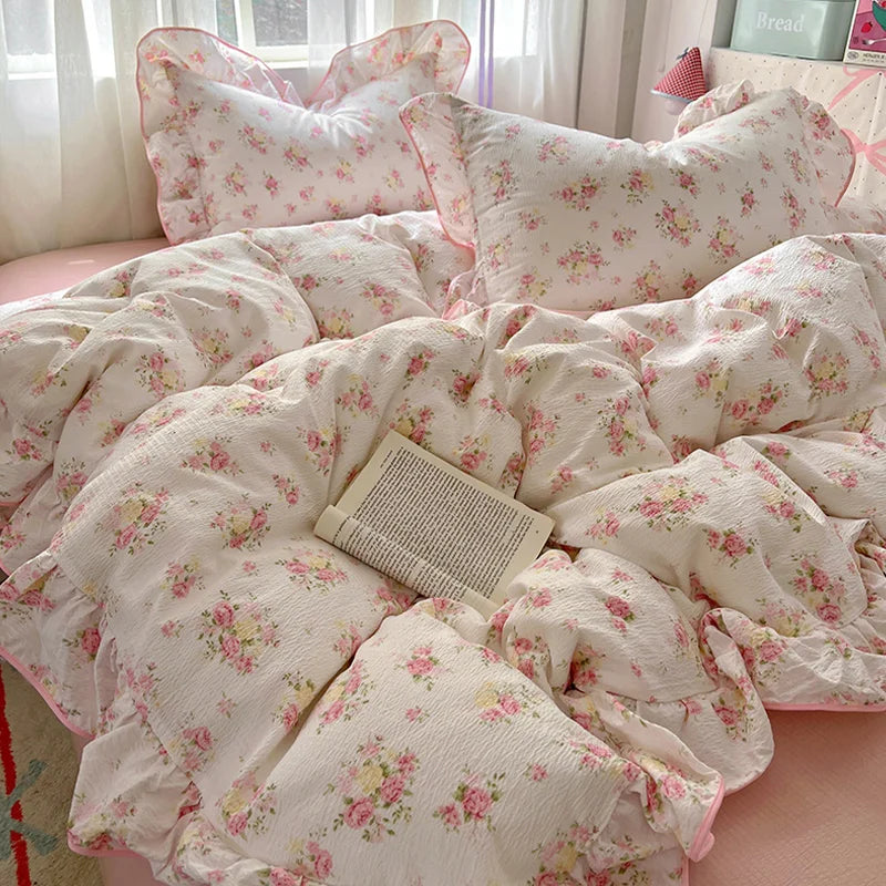 A floral duvet cover set in white with pink accents, featuring a patterned duvet, pillowcases, and flat sheet.