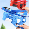 Two foam glider plane launchers, one red and one blue, are held by hands against a blurred green background.
