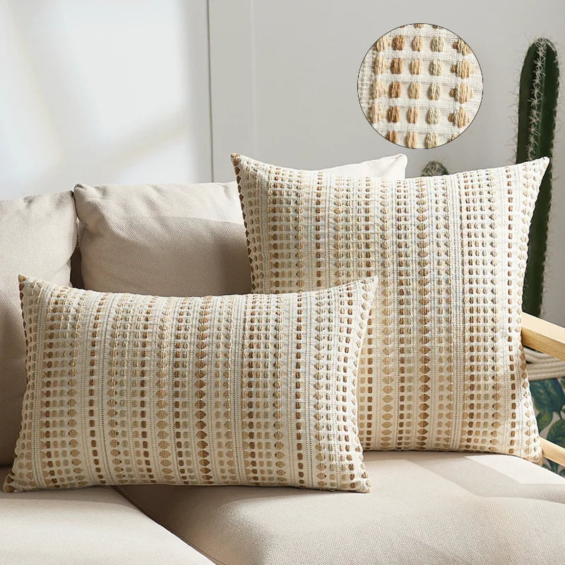 Two beige linen pillow covers with a textured weave and a circular cactus pattern displayed on a light sofa.