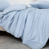 Luxuriöse hellblaue Bambus-Duvetcover-Set, drapiert auf einem Bett.