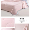 A pink ice silk cooling blanket draped over a surface, showing its soft texture and light gray trim.