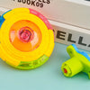 A yellow and pink glowing musical spinning top is shown next to its disassembled parts on a light blue surface.