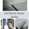 A hand is wiping a surface with a gray microfiber cloth, demonstrating that the product does not leave water stains.