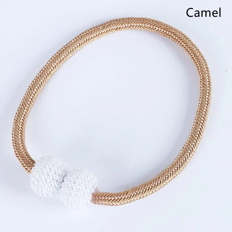 A round woven beige magnetic curtain clip with three white pearl accents.