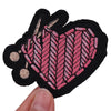 A set of black embroidered iron-on patches shaped like hearts with pink and beige stitching.