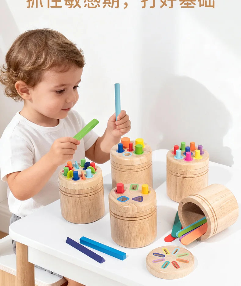 A toddler is sorting colored wooden sticks into a wooden container, demonstrating fine motor skills.