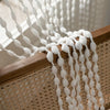 White bohemian tassel curtain with lantern strands hanging over a wooden frame