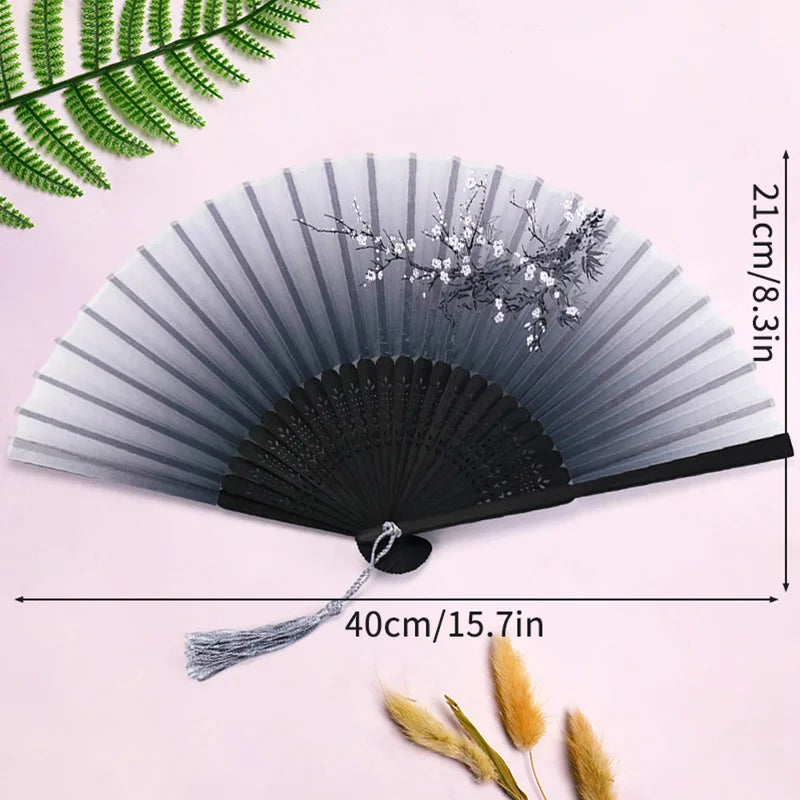 A gray and black vintage lace folding hand fan with a durable handle displayed against a pink background.