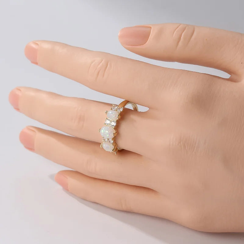 Une main portant une bague ovale en opale synthétique avec placage d'or à l'annulaire.