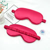 A bright pink silk sleep mask with a ruffled edge is displayed on a white background.